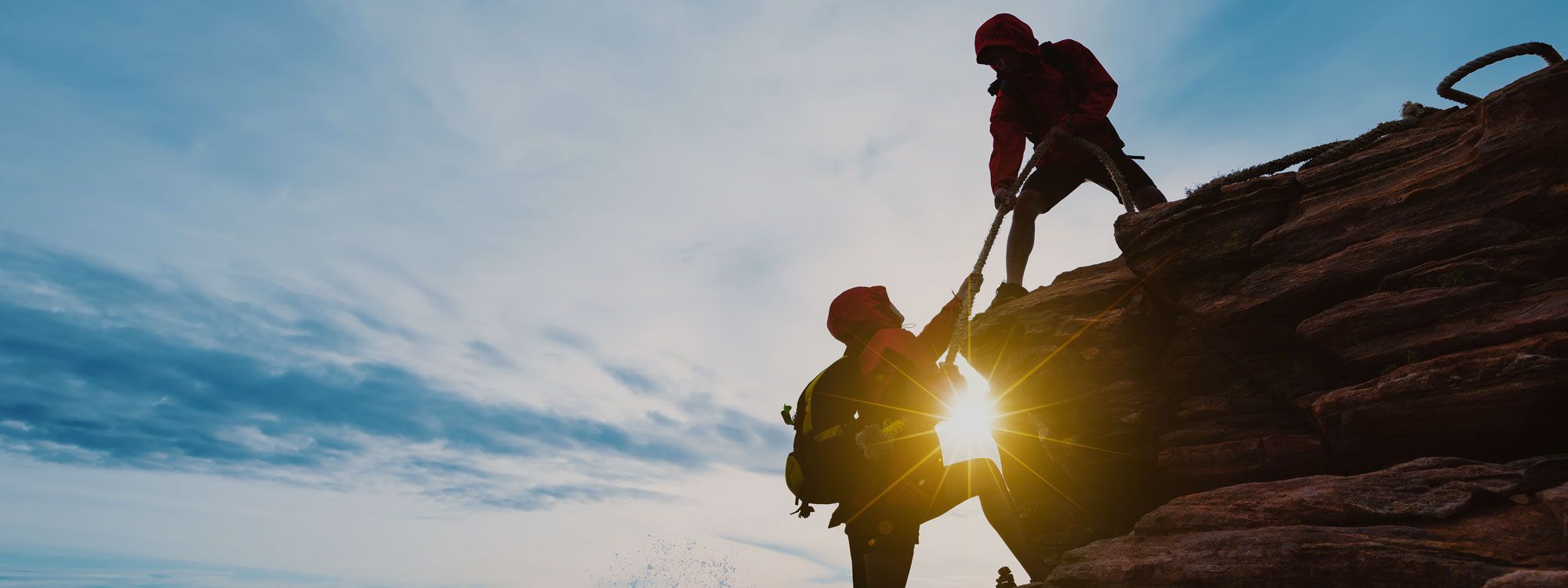 Climbers helping each other up mountain